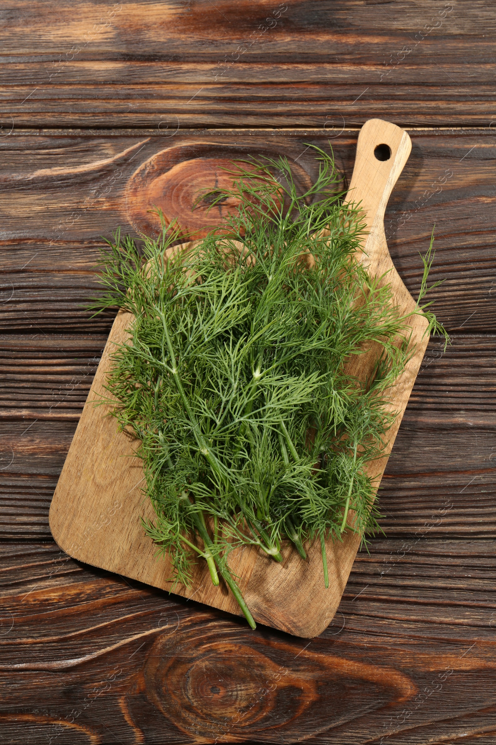 Photo of Board with fresh green dill on wooden table, top view