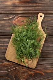 Board with fresh green dill on wooden table, top view