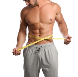 Young man with slim body using measuring tape on white background, closeup view