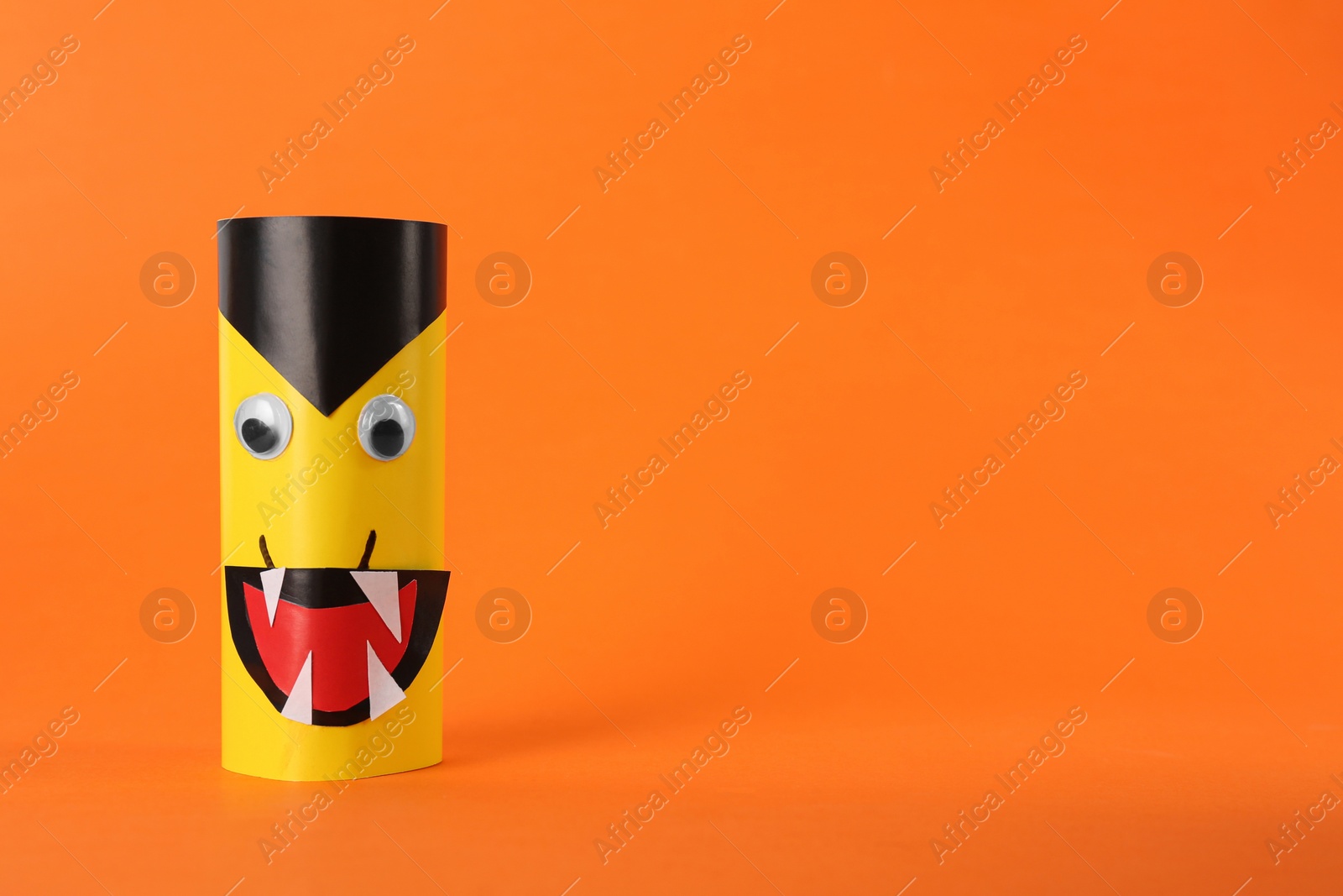 Photo of Funny yellow monster on orange background, space for text. Halloween decoration