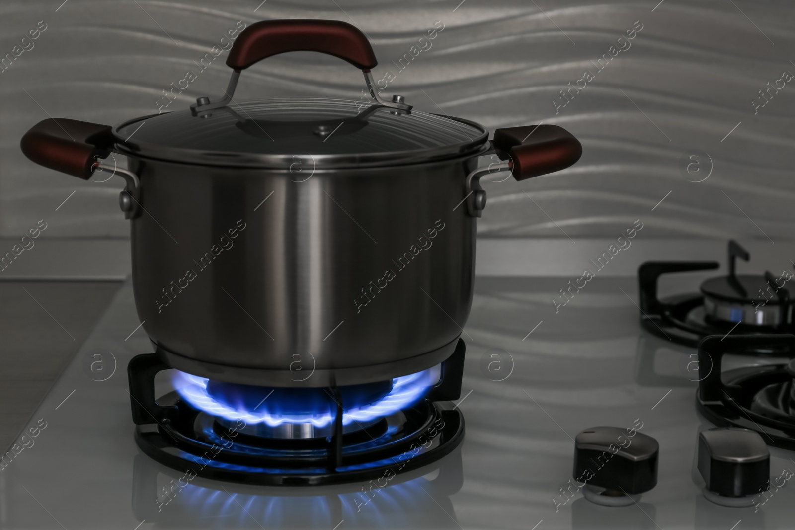 Photo of Pot on modern gas cooktop in kitchen