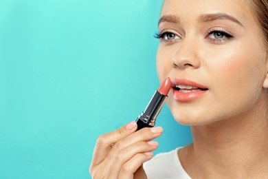 Photo of Beautiful woman applying nude lipstick on color background. Space for text