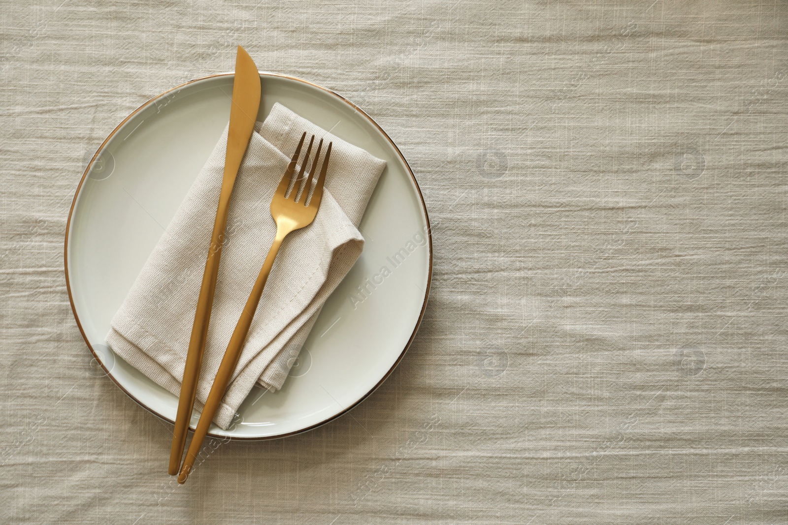 Photo of Stylish setting with cutlery, napkin and plate on light table, top view. Space for text