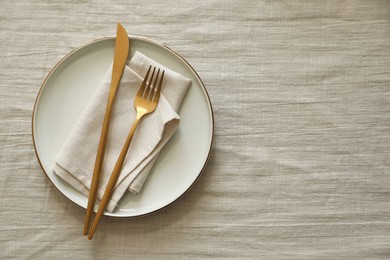 Stylish setting with cutlery, napkin and plate on light table, top view. Space for text