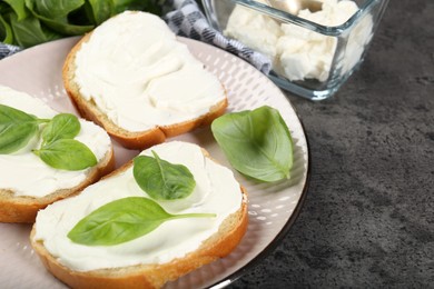 Photo of Delicious sandwiches with cream cheese and basil leaves on grey table, closeup