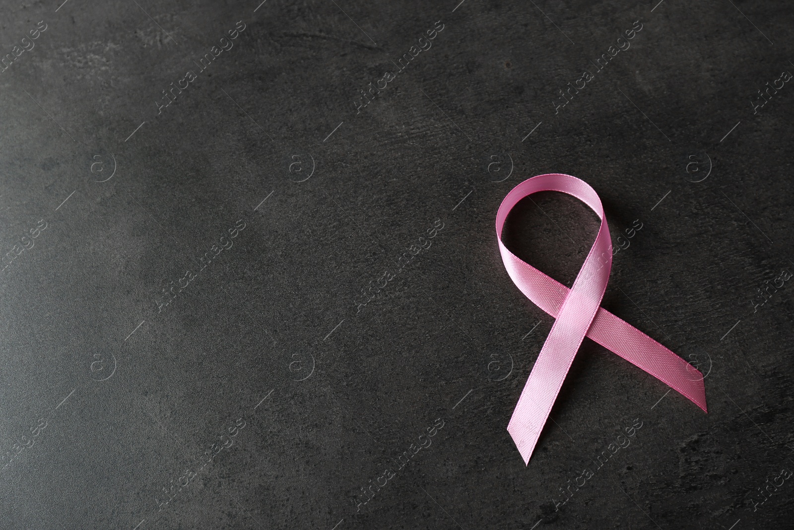 Photo of Pink ribbon and space for text on dark background. Breast cancer awareness concept