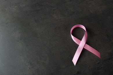Photo of Pink ribbon and space for text on dark background. Breast cancer awareness concept