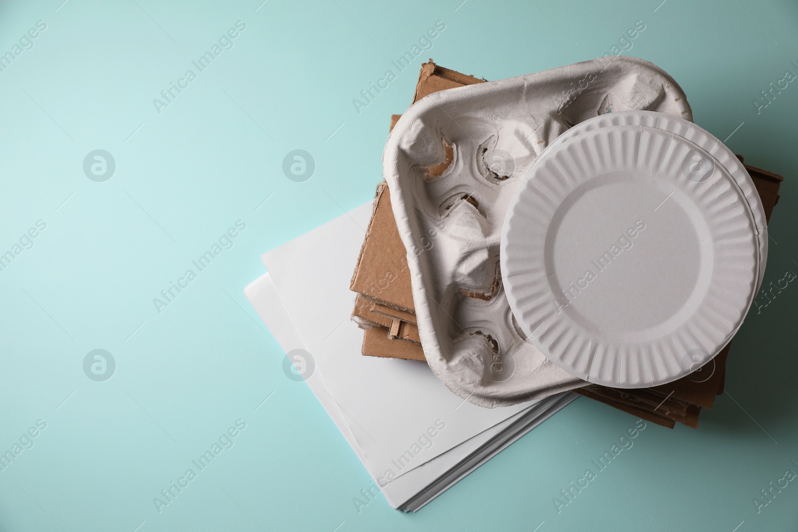 Photo of Heap of waste paper on turquoise background, top view. Space for text