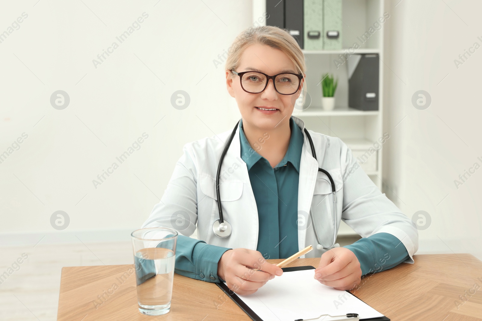 Photo of Professional doctor sitting at wooden table in clinic