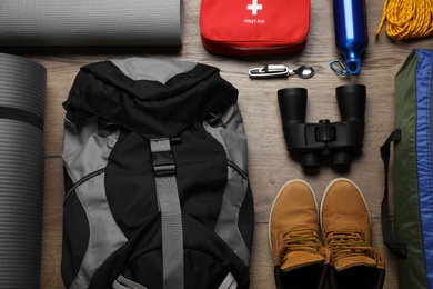 Photo of Flat lay composition with different camping equipment on wooden background