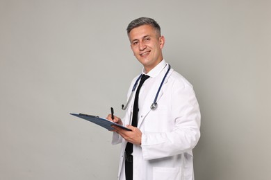 Photo of Doctor with stethoscope and clipboard on grey background