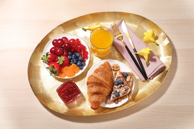 Delicious breakfast with croissant on wooden table, top view