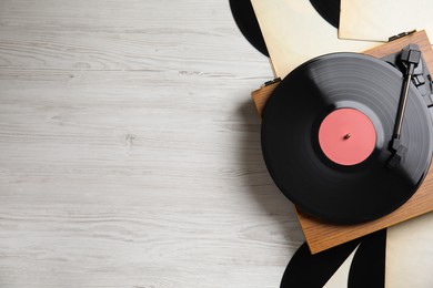 Photo of Modern player and vinyl records on white wooden background, flat lay. Space for text