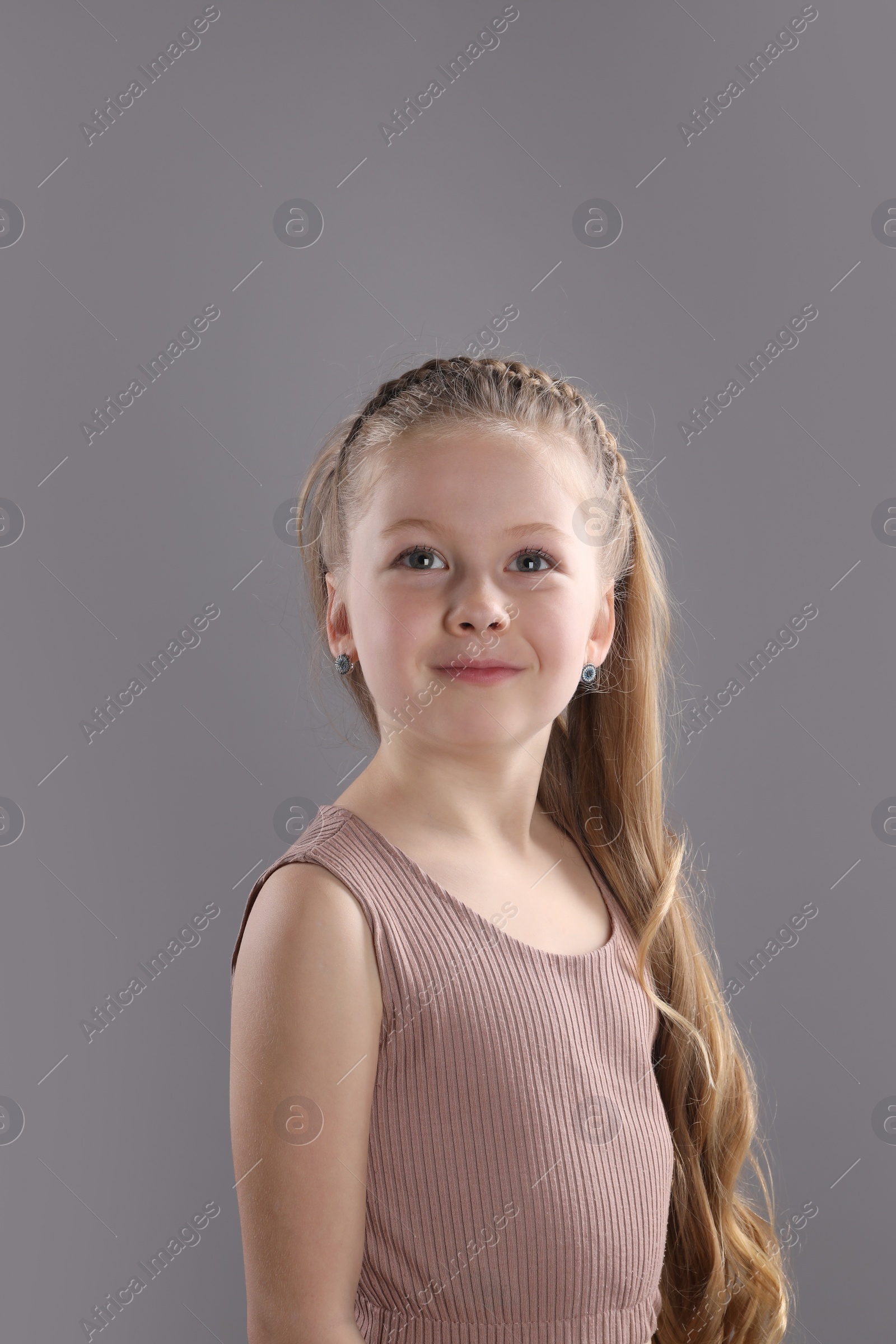 Photo of Little girl with braided hair on grey background
