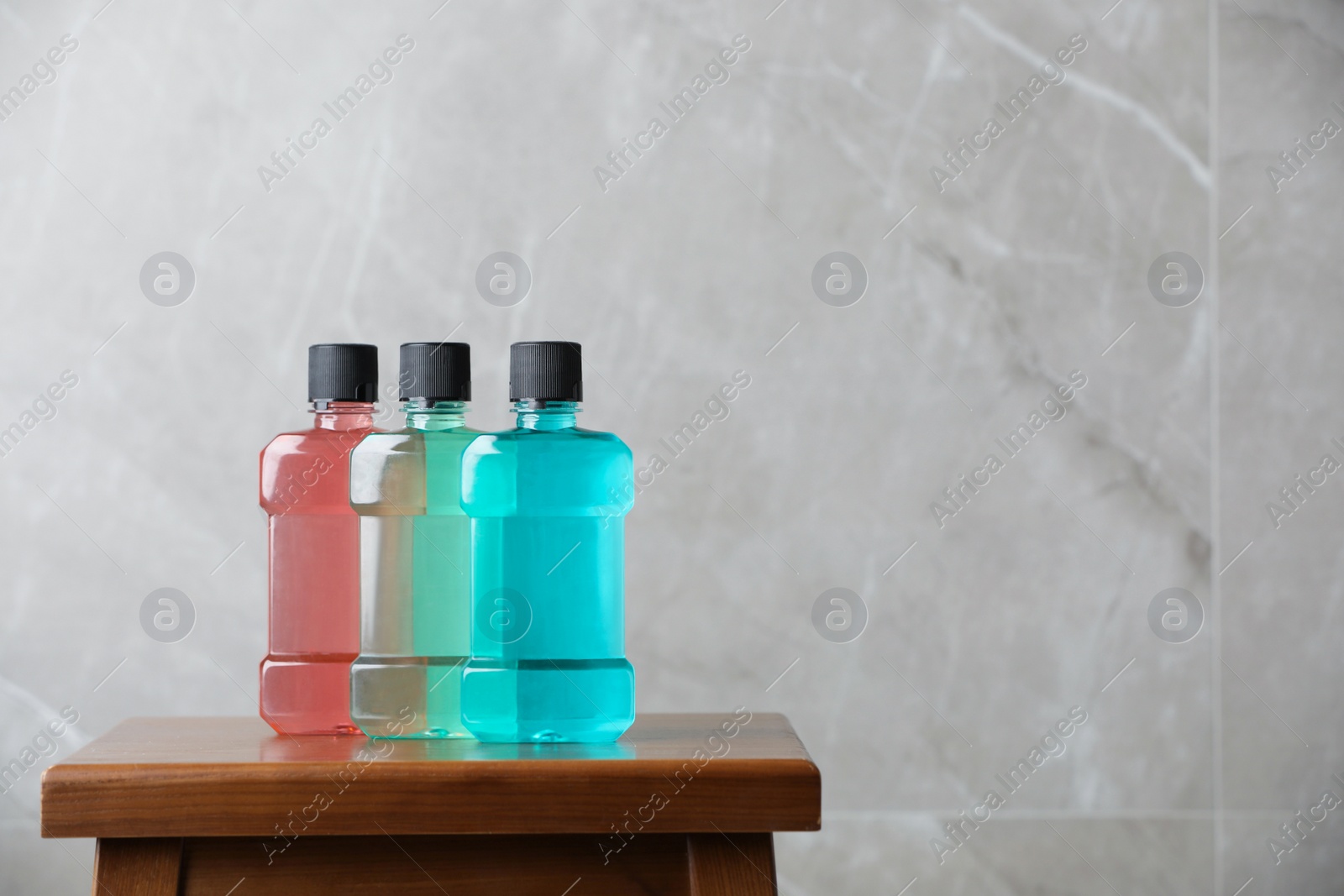 Photo of Bottles with mouthwash on wooden table, space for text