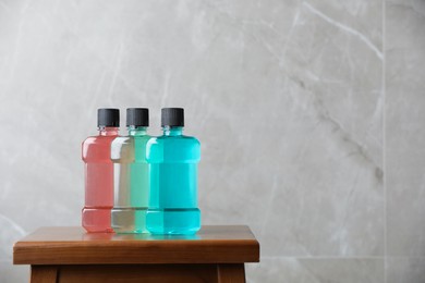 Photo of Bottles with mouthwash on wooden table, space for text