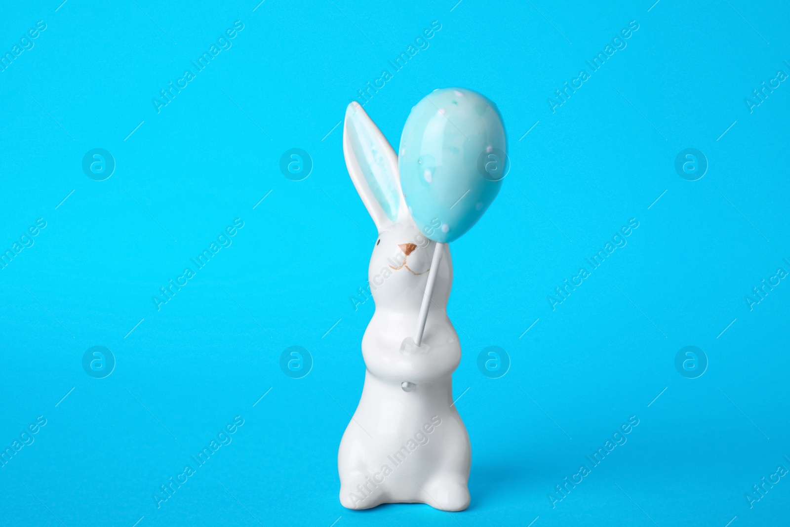 Photo of Bunny ceramic figure as Easter decor on blue background