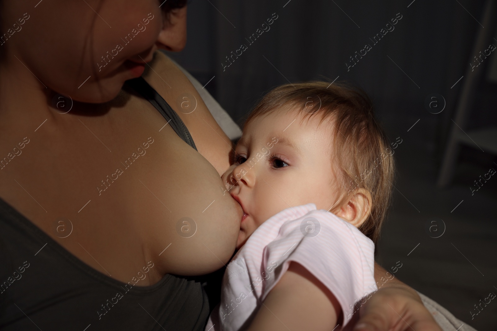 Photo of Woman breastfeeding her little baby at home, closeup