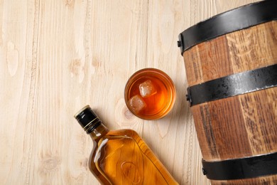 Photo of Barrel, bottle and glass of tasty whiskey on wooden table, flat lay. Space for text