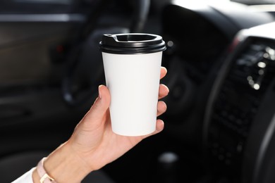 Coffee to go. Woman with paper cup of drink in car, closeup