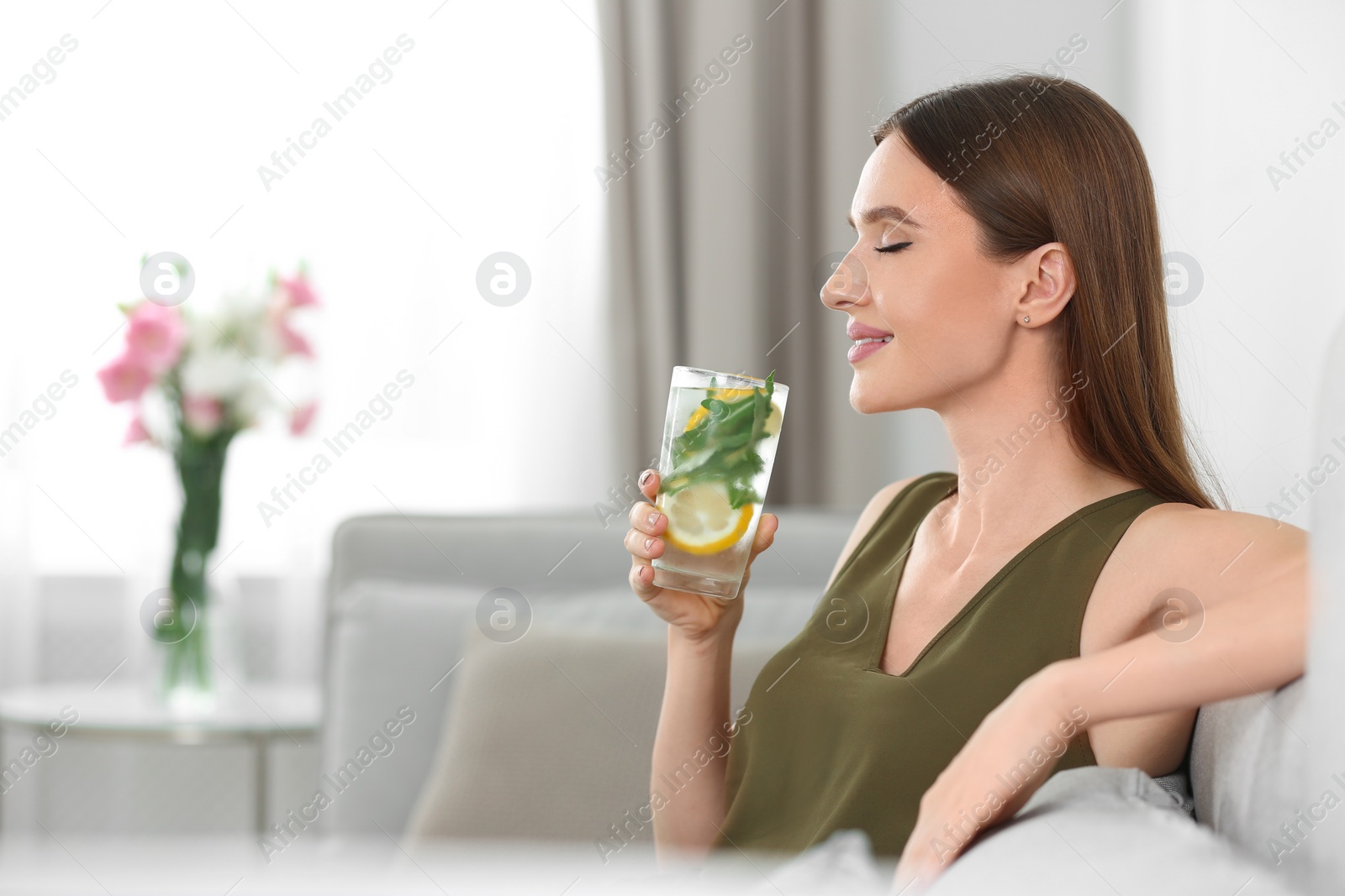 Photo of Young woman with lemonade at home. Refreshing drink