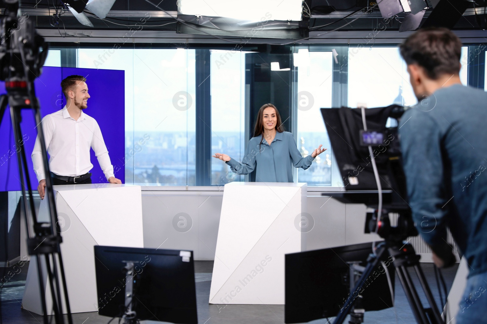 Photo of Presenters and video camera operator working in studio. News broadcasting