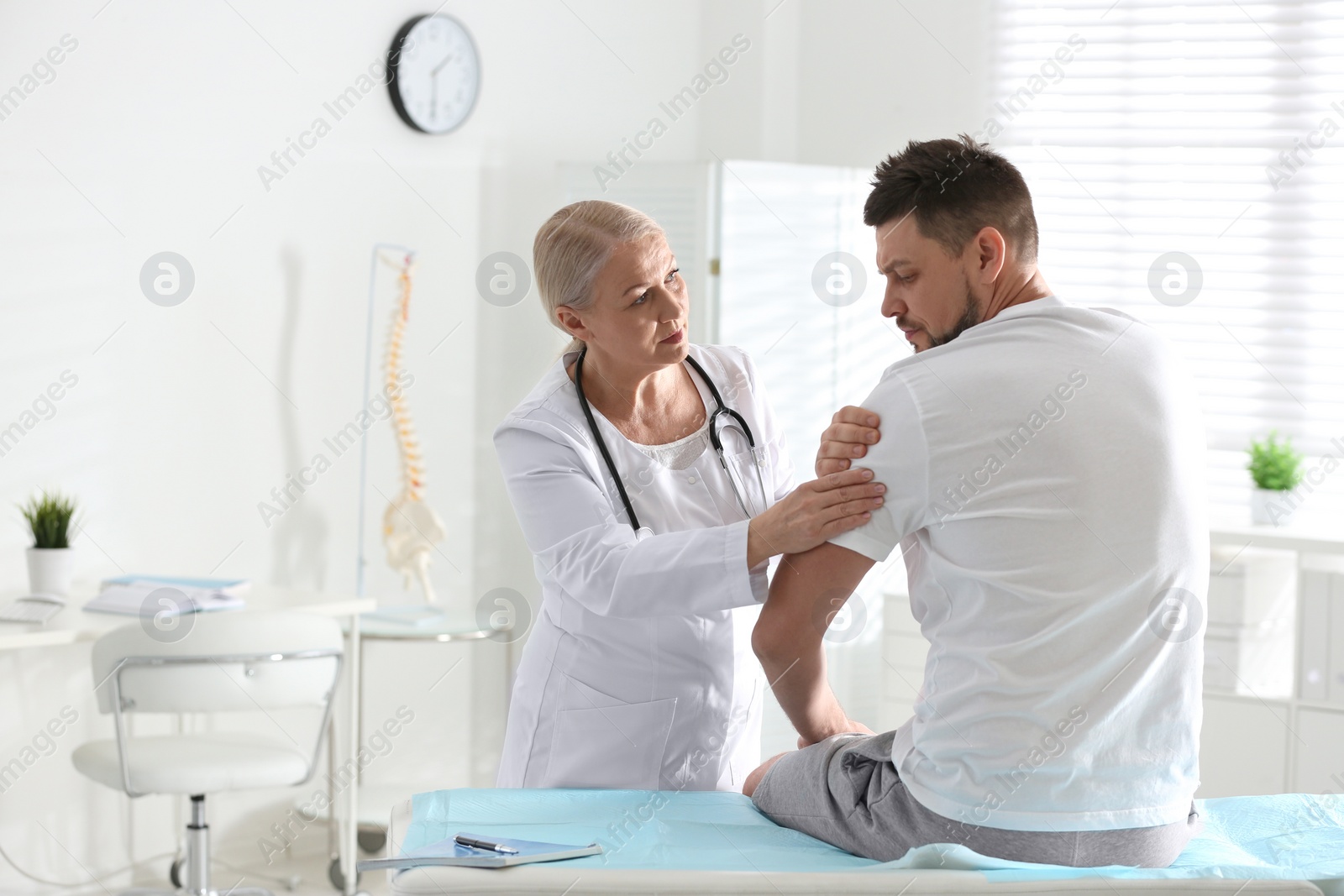 Photo of Male orthopedist examining patient's arm in clinic