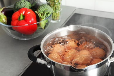 Photo of Cooking chicken eggs in pot on electric stove at kitchen