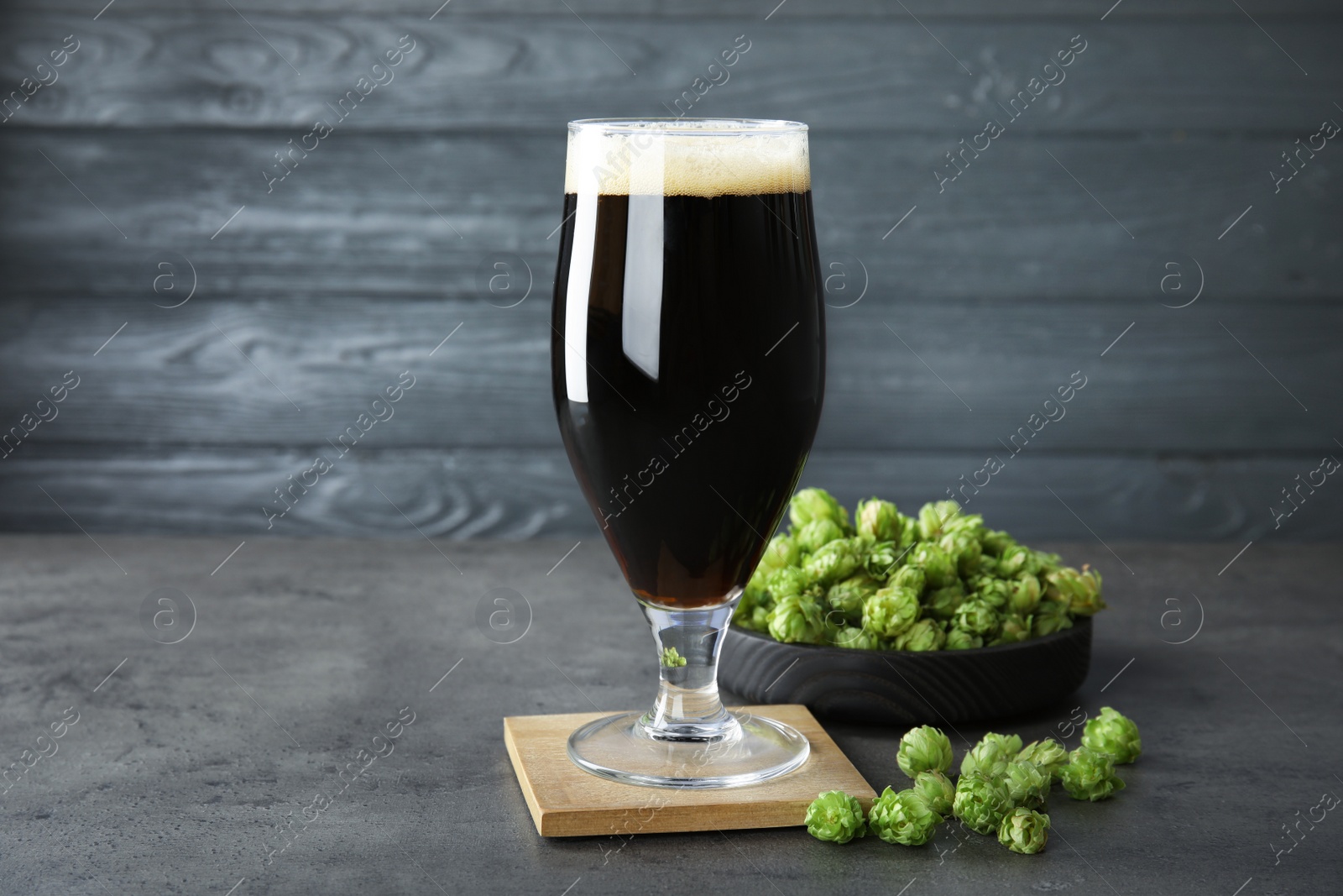 Photo of Composition with tasty beer and fresh green hops on grey table