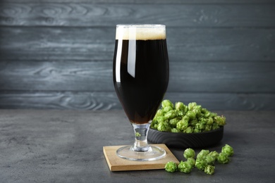 Composition with tasty beer and fresh green hops on grey table