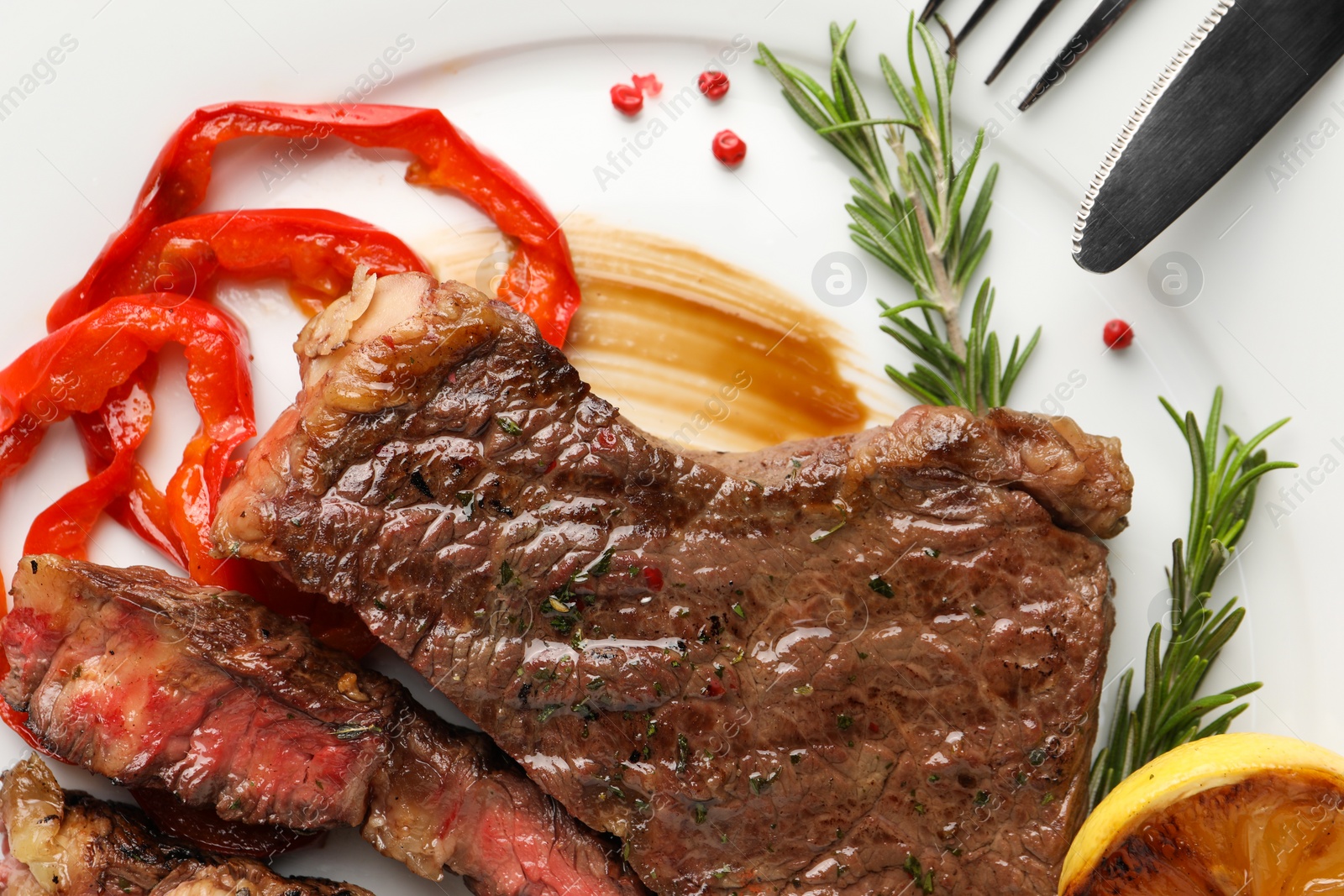 Photo of Delicious grilled beef steak with pepper and spices served on plate, top view