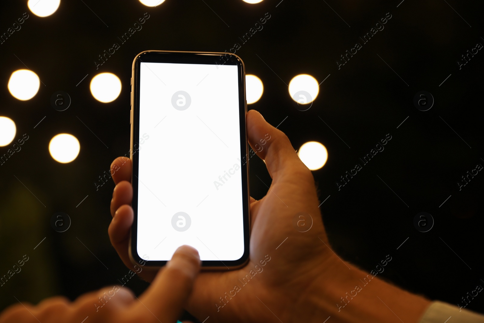 Photo of Man using modern mobile phone outdoors at night, closeup