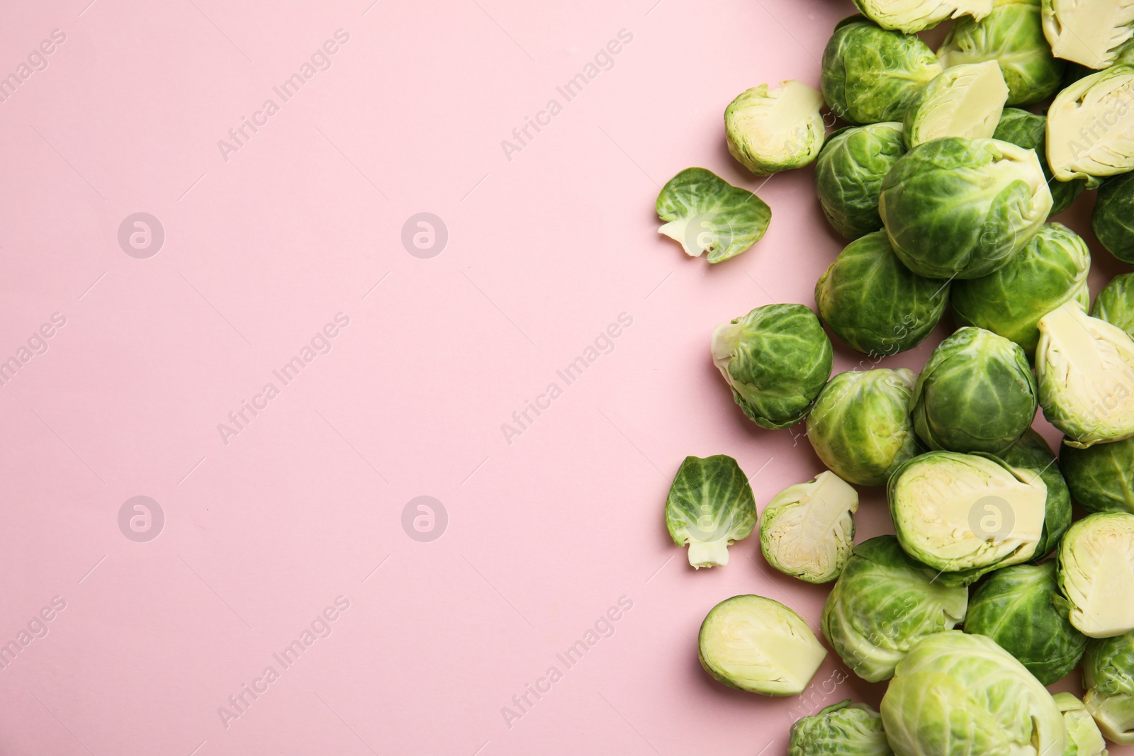 Photo of Fresh Brussels sprouts on pink background, flat lay. Space for text