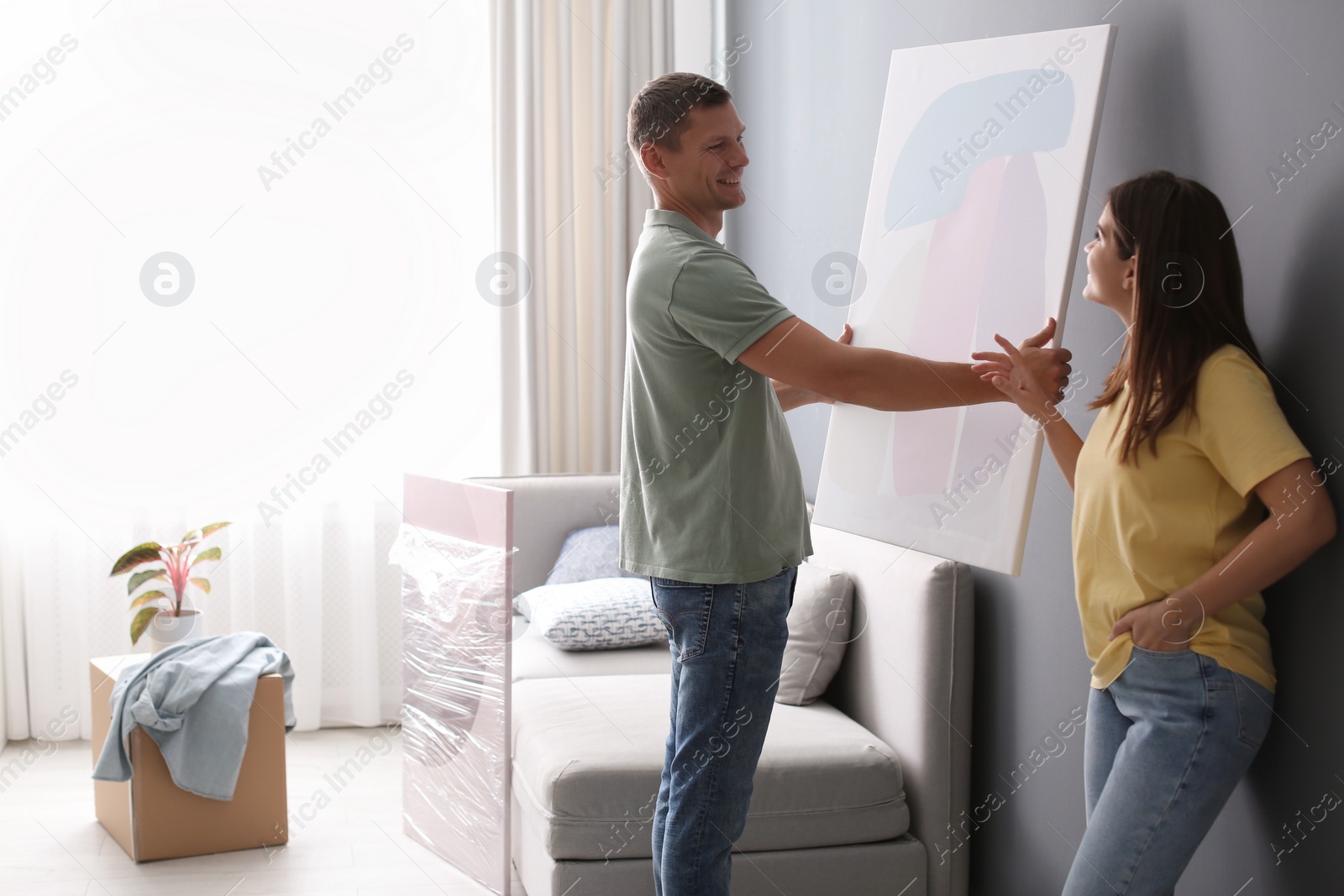 Photo of Couple decorating room with pictures together. Interior design