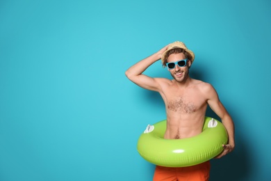 Photo of Young man in shorts with inflatable ring against color background. Space for text