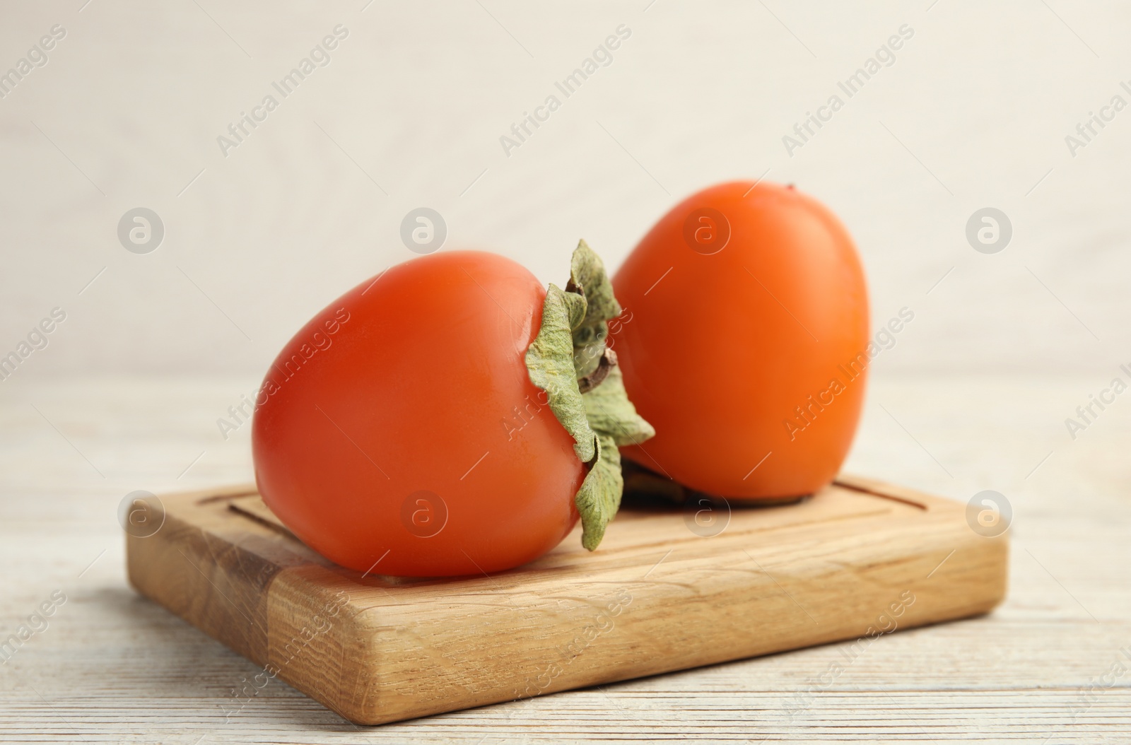 Photo of Tasty ripe persimmons on white wooden table, closeup