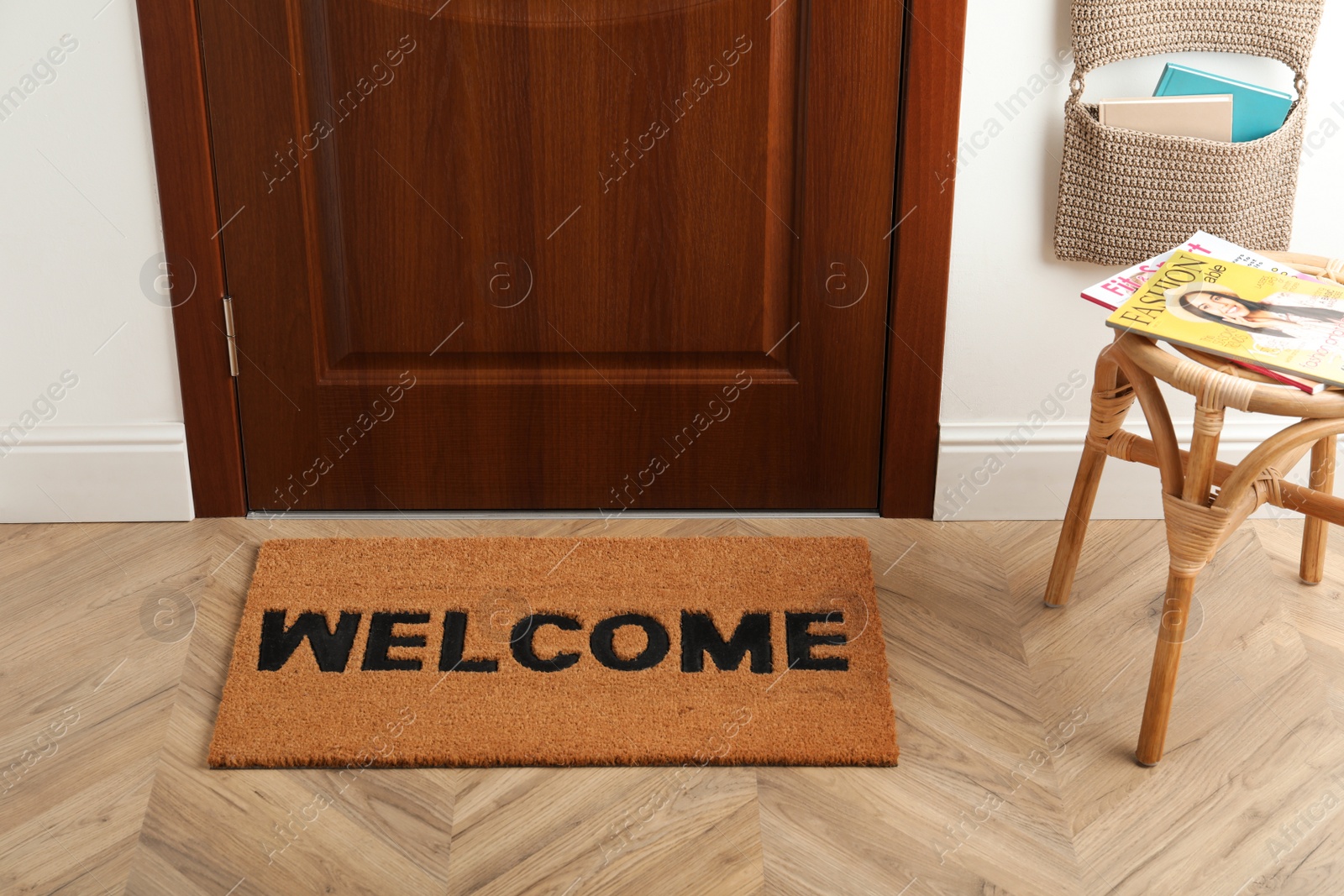 Photo of Door mat with word Welcome on wooden floor in hall