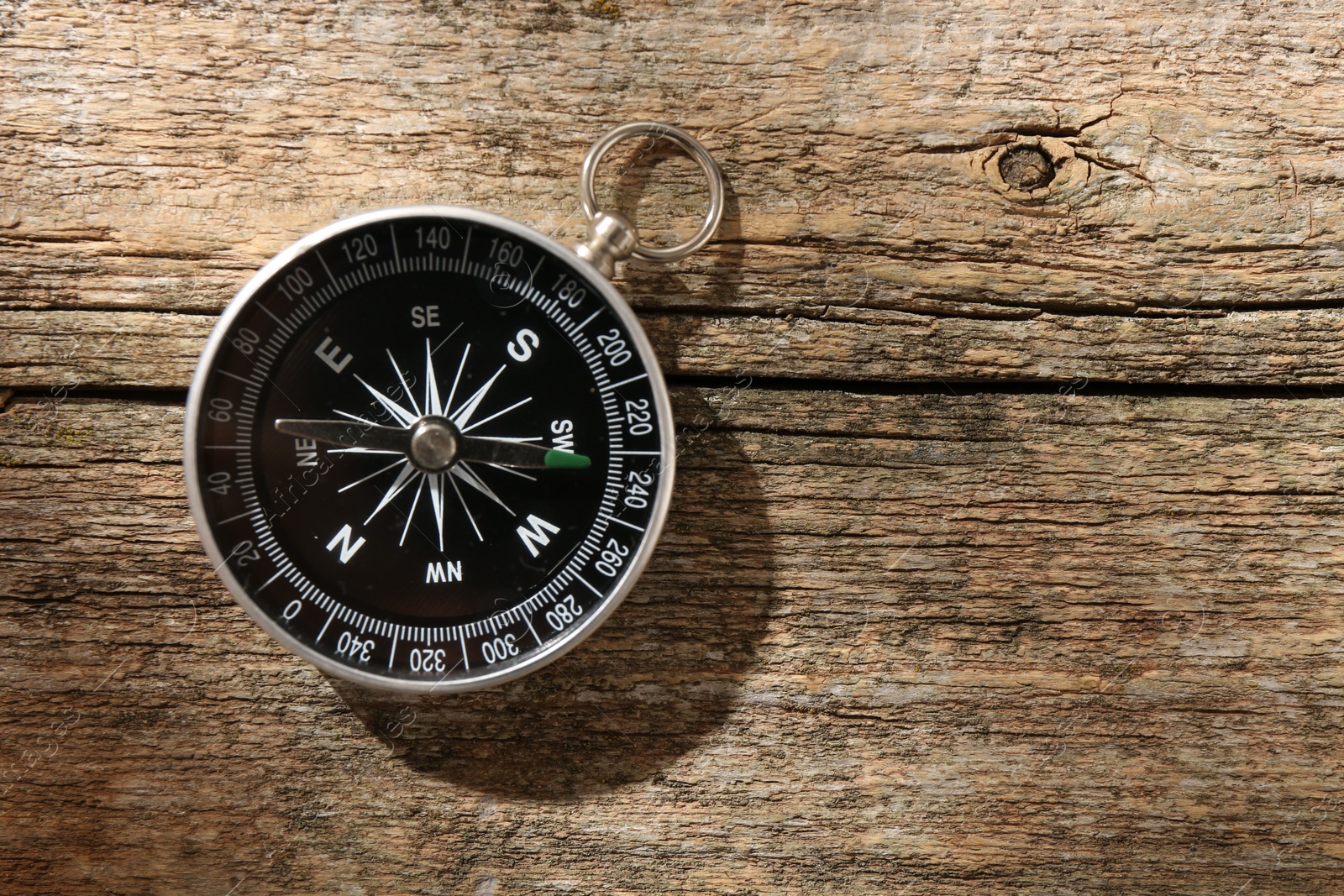 Photo of One compass on wooden table, top view. Space for text