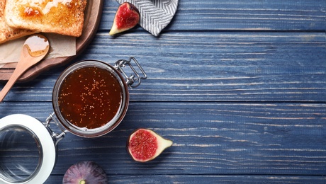 Flat lay composition with delicious fig jam on blue wooden table. Space for text