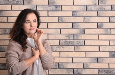 Portrait of beautiful older woman against brick wall with space for text