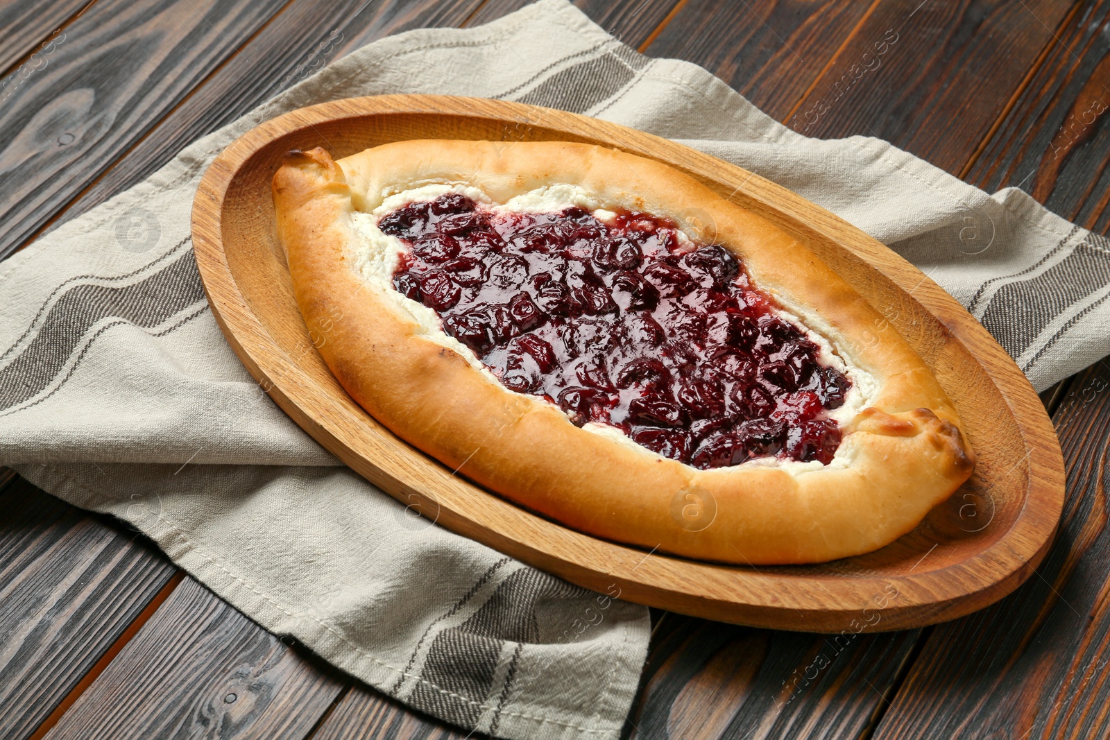 Photo of Delicious sweet cottage cheese pastry with cherry jam on wooden table