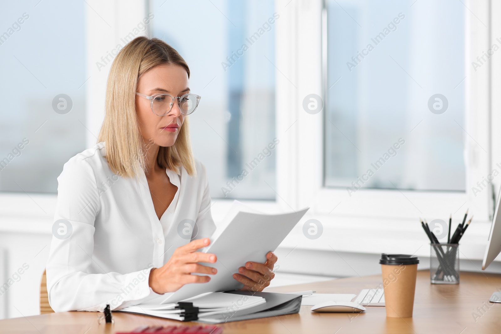 Photo of Woman working with documents at wooden table in office