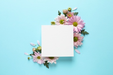 Photo of Beautiful chamomile flowers and paper card on color background, flat lay with space for text