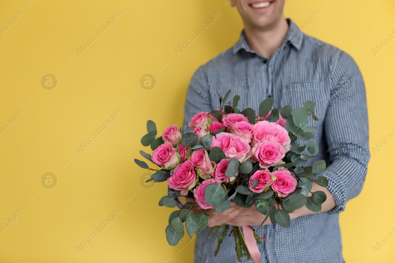 Photo of Male florist holding bouquet of beautiful flowers on color background