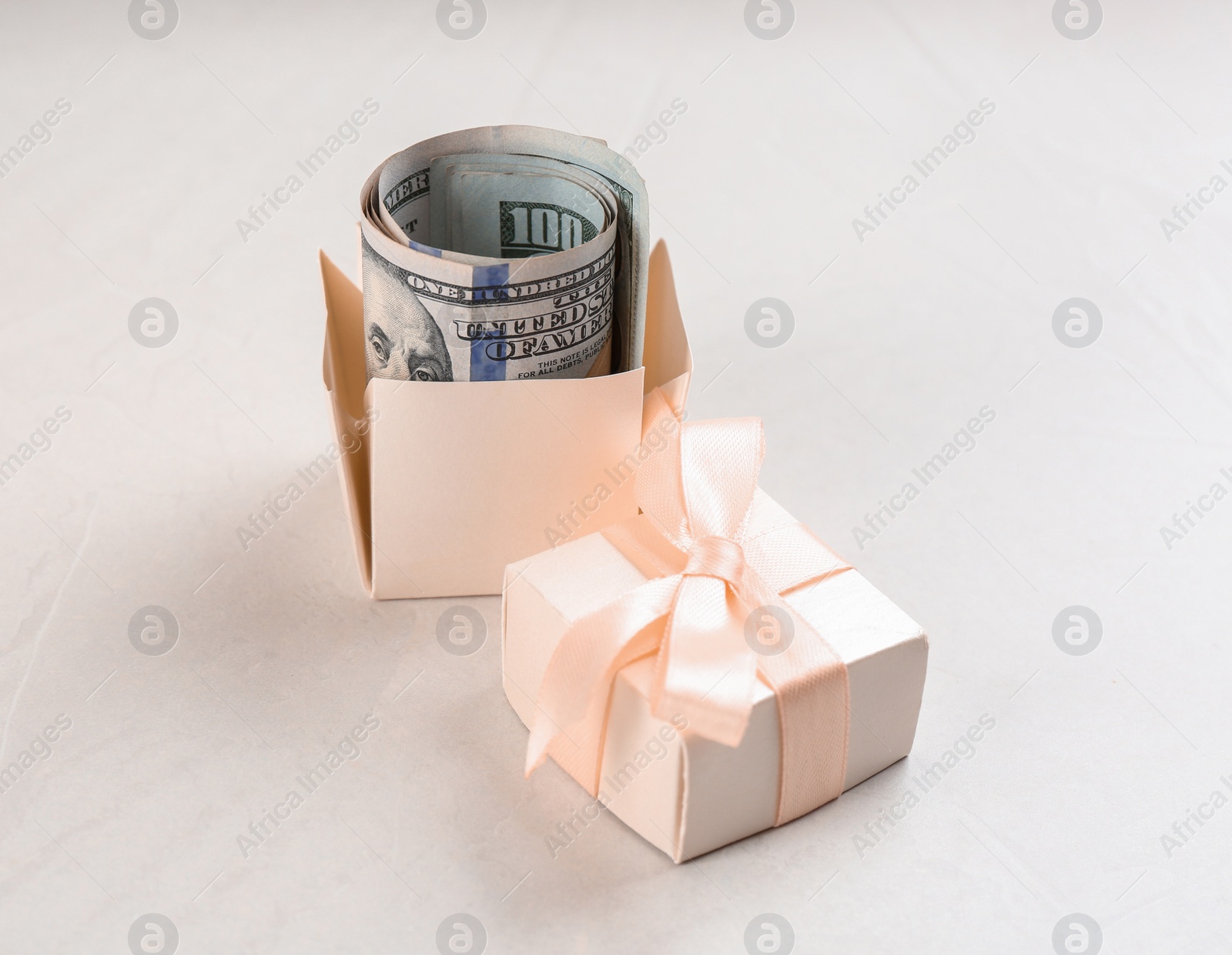 Photo of Gift box with dollar bills on light grey stone table