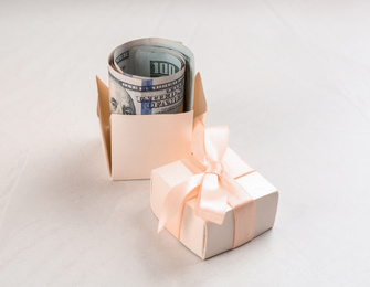 Gift box with dollar bills on light grey stone table