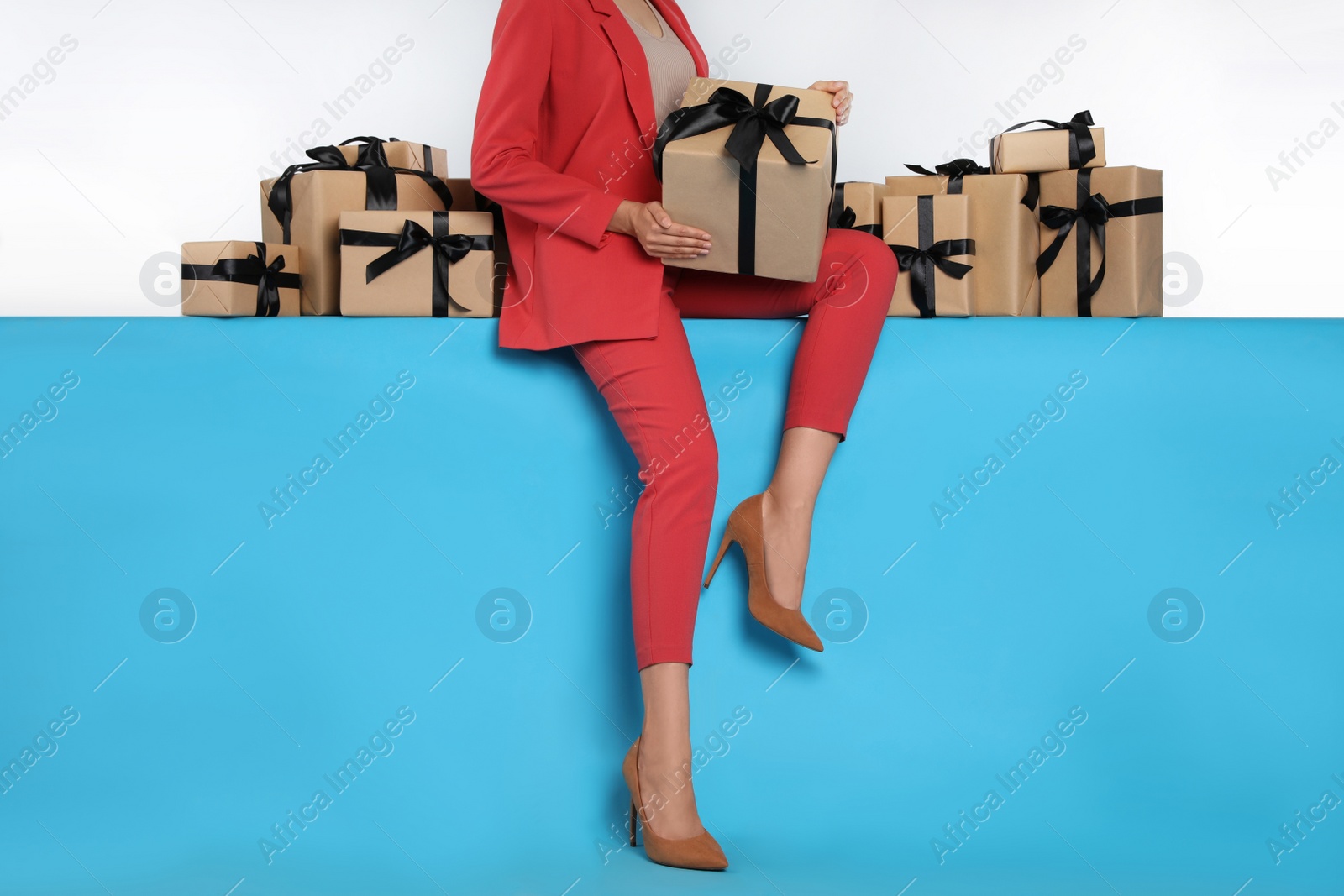 Photo of Woman and gift boxes on light blue background, closeup. Black Friday