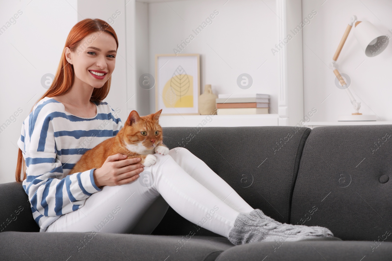 Photo of Happy woman with her cute cat on sofa at home