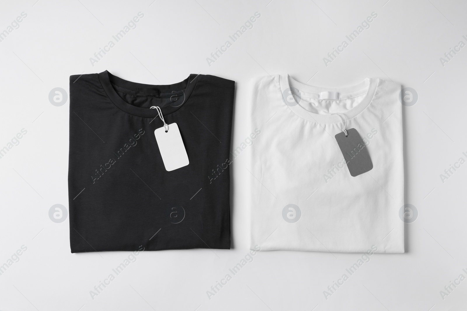 Photo of Stylish T-shirts with labels on white background, top view