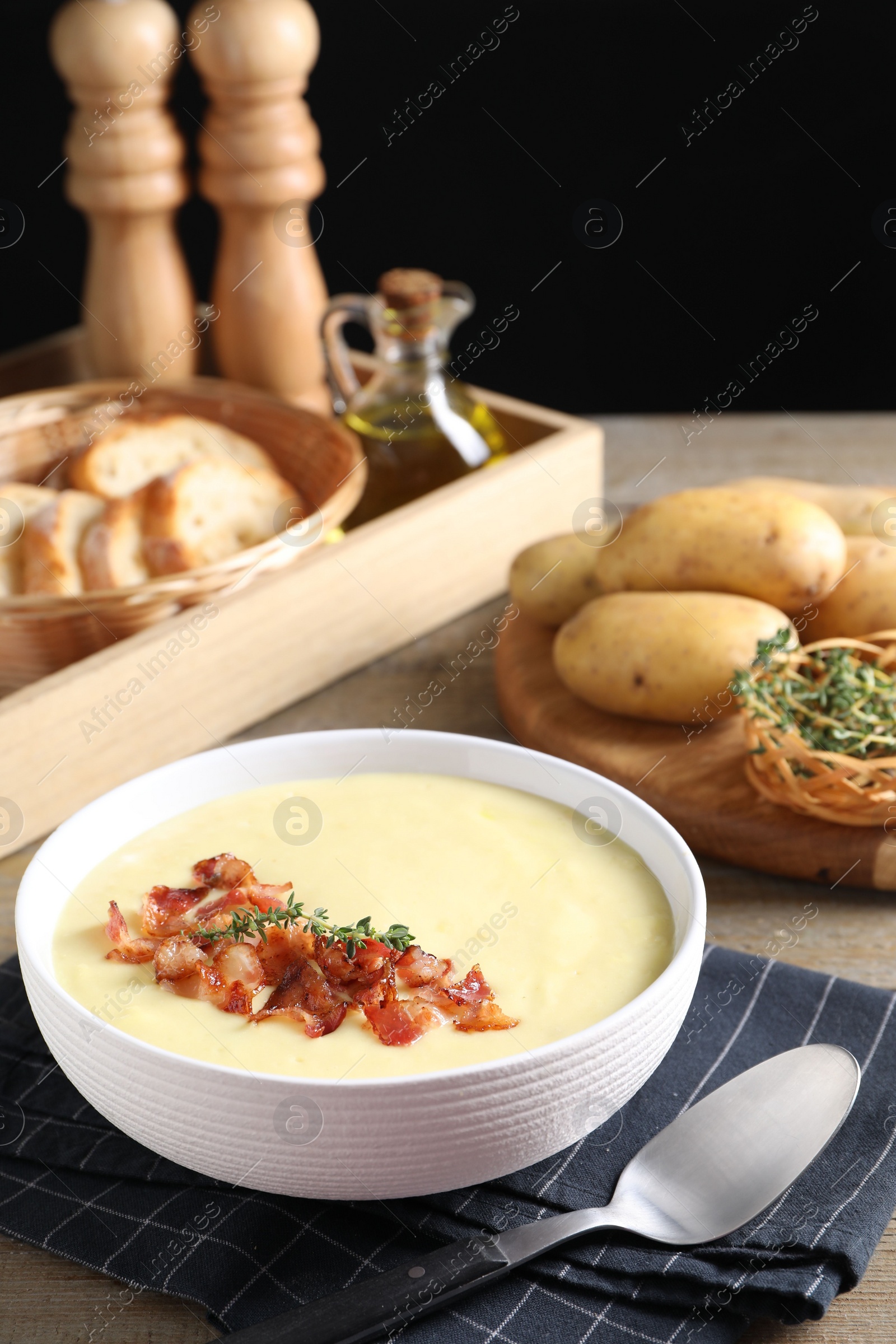 Photo of Tasty potato soup with bacon and rosemary in bowl served on wooden table